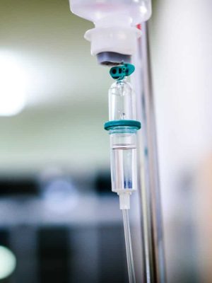 Intravenous therapy iv infusion set and bottle on a pole. Liquid saline is slowly dripping drops of drugs, medicine or antibiotic therapy and surgery recovery in a hospital or clinic.
